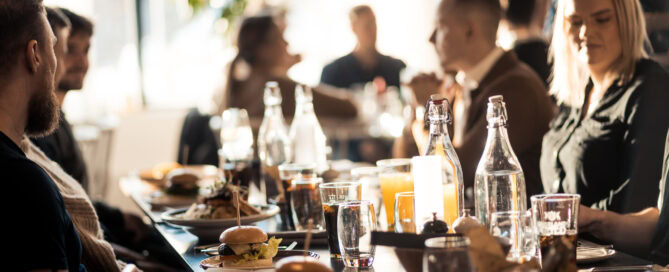 Vegetariska och klassiska burgare på ett socialt matbord under lunch eller middag, blick över ett glädjefyllt sällskap, perfekt för företagstillställningar och fester.