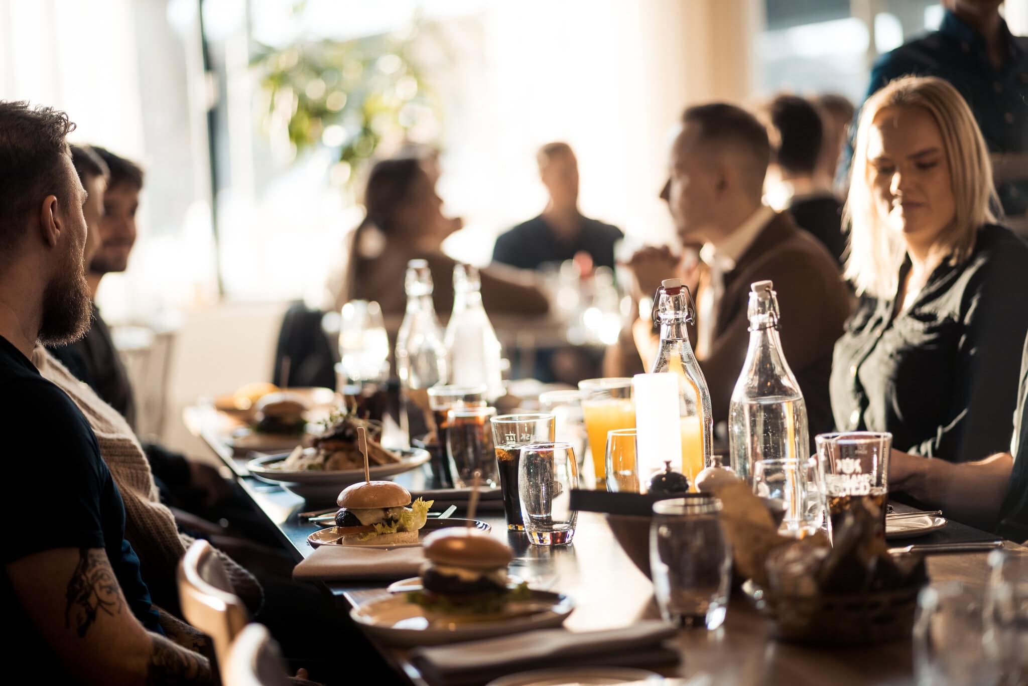 Vegetariska och klassiska burgare på ett socialt matbord under lunch eller middag, blick över ett glädjefyllt sällskap, perfekt för företagstillställningar och fester.