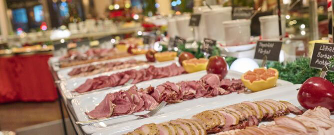 Vällagade charkuterier och delikatesser på julbuffé, perfekt för fest och gemenskap. Snyggt upplägg med skinka, kött och tillbehör i festlig miljö, idealiskt för catering och fester.