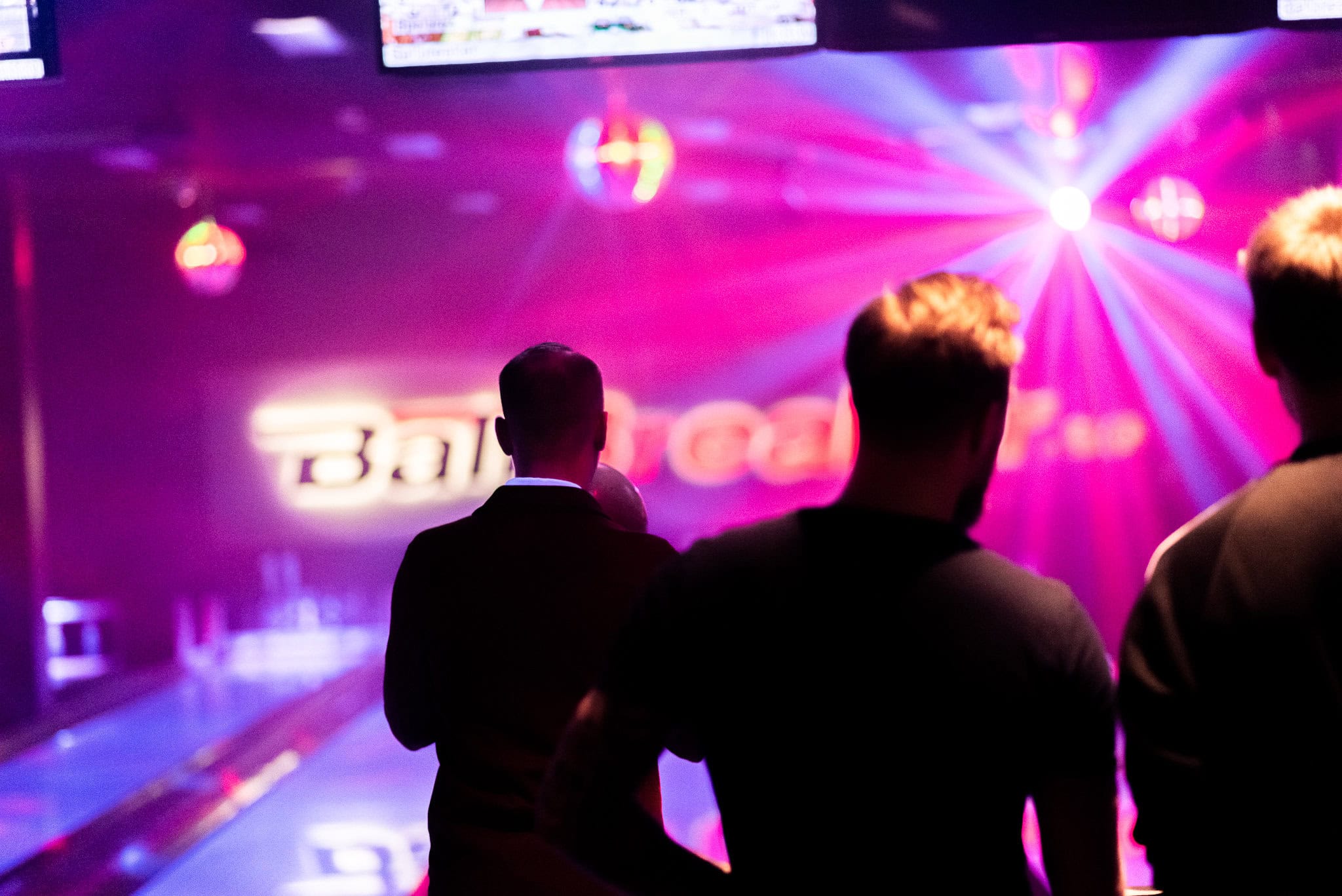 Festgäster som spelar bowling på Ballbreaker med neonljus och färgglada lampor i en livlig och modern bowlinghall. Idealisk bild för att visa en rolig och social aktivitet i en avslappnad miljö.